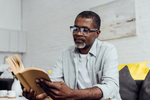 Man reading book with glasses on 