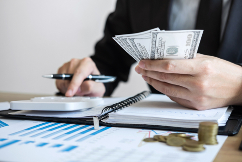 person counting money with calculator