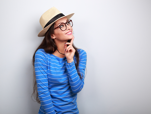 A woman with glasses smiling and looking up.